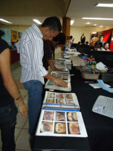 Clients browse albums of tattoo designs at the Tattoo Fest in Oaxaca, Mexico. © Alvin Starkman, 2011