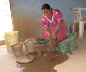 Maria, one of the women potters of San Marcos Tlapazola, Oaxaca, mixes dry, powederd clay with water and kneads it by hand. This talented Mexican artisan will transform the clay into finely crafted ceramic vessels that she will sell in the local Mexican market. © Alvin Starkman, 2010