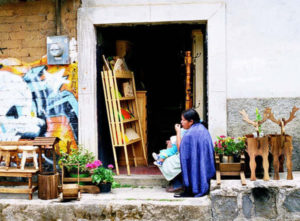 Draped in Michoacan's characteristic blue rebozo, a woman and her child wait for customers outside her furniture shop. Reindeer to her right are a part of the designs on sale.