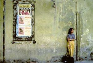 A young Mexicana waits patiently for the bus near a billboard advertising the local bull-fights.