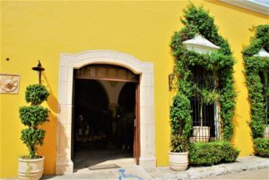 Entrance to Kinich. Buildings in Izamal are washed with yellow and accented with white trim. © 2020 Jane Simon Ammeson